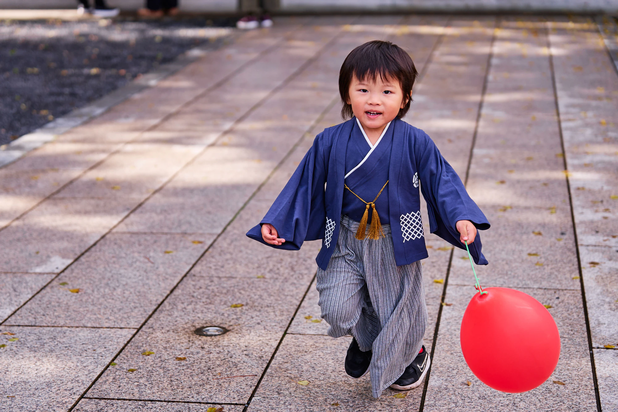 赤い風船を持って境内を走る羽織袴の男の子