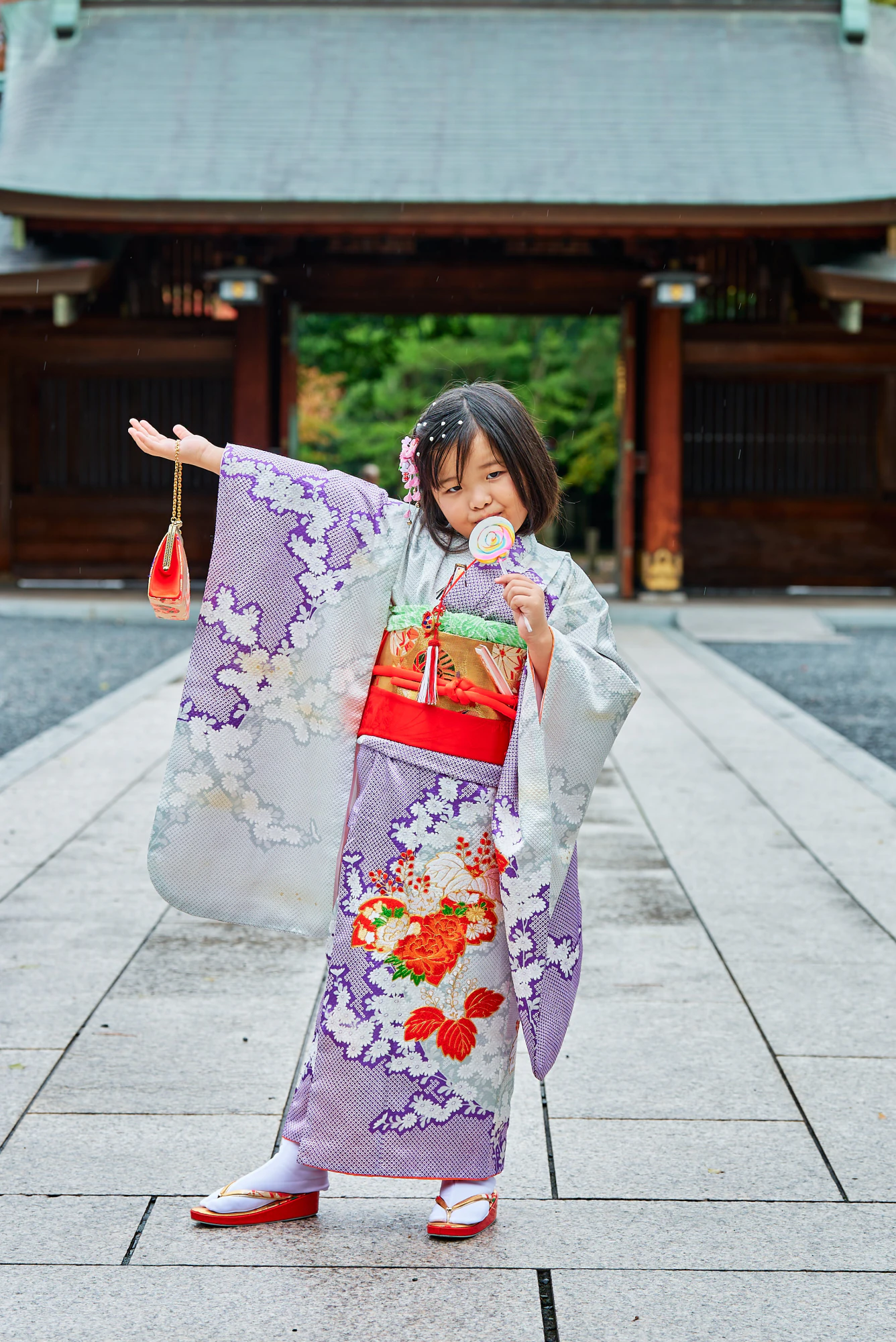 千歳飴を持ってポーズをとる着物姿の女の子