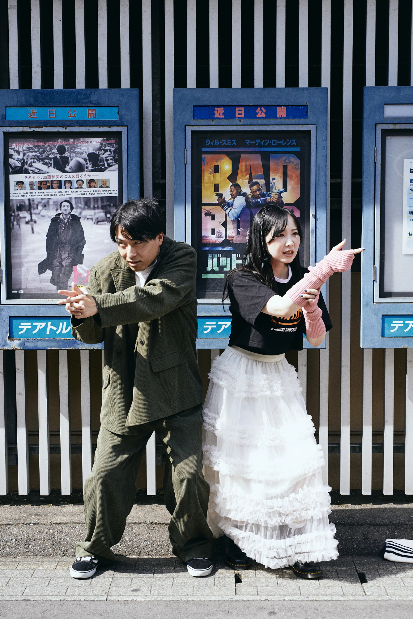 映画館のポスター壁の前で遊ぶふたり