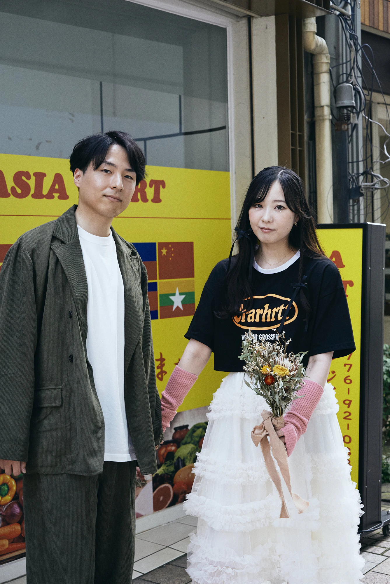 商店街の店先でポーズをとるふたり