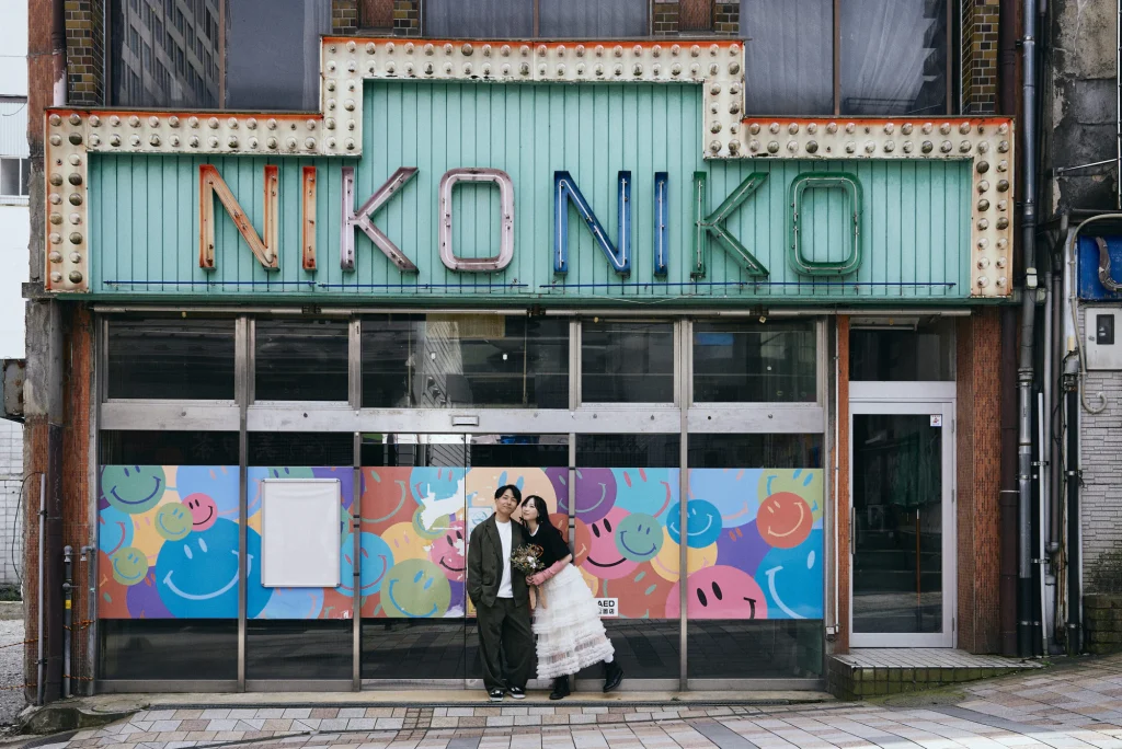 レトロな看板の店先に立つふたり ストリートフォトウェディング