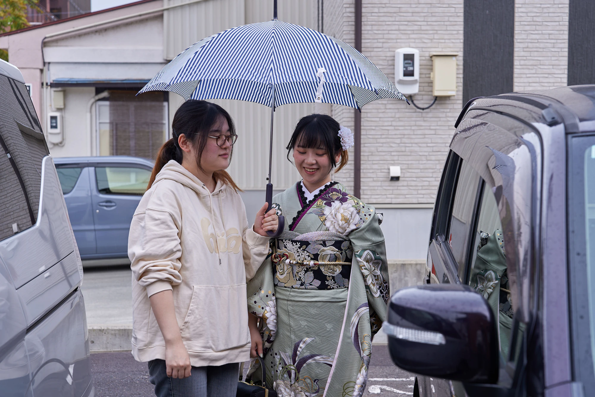 傘を差しかけてもらいながら移動する振袖姿