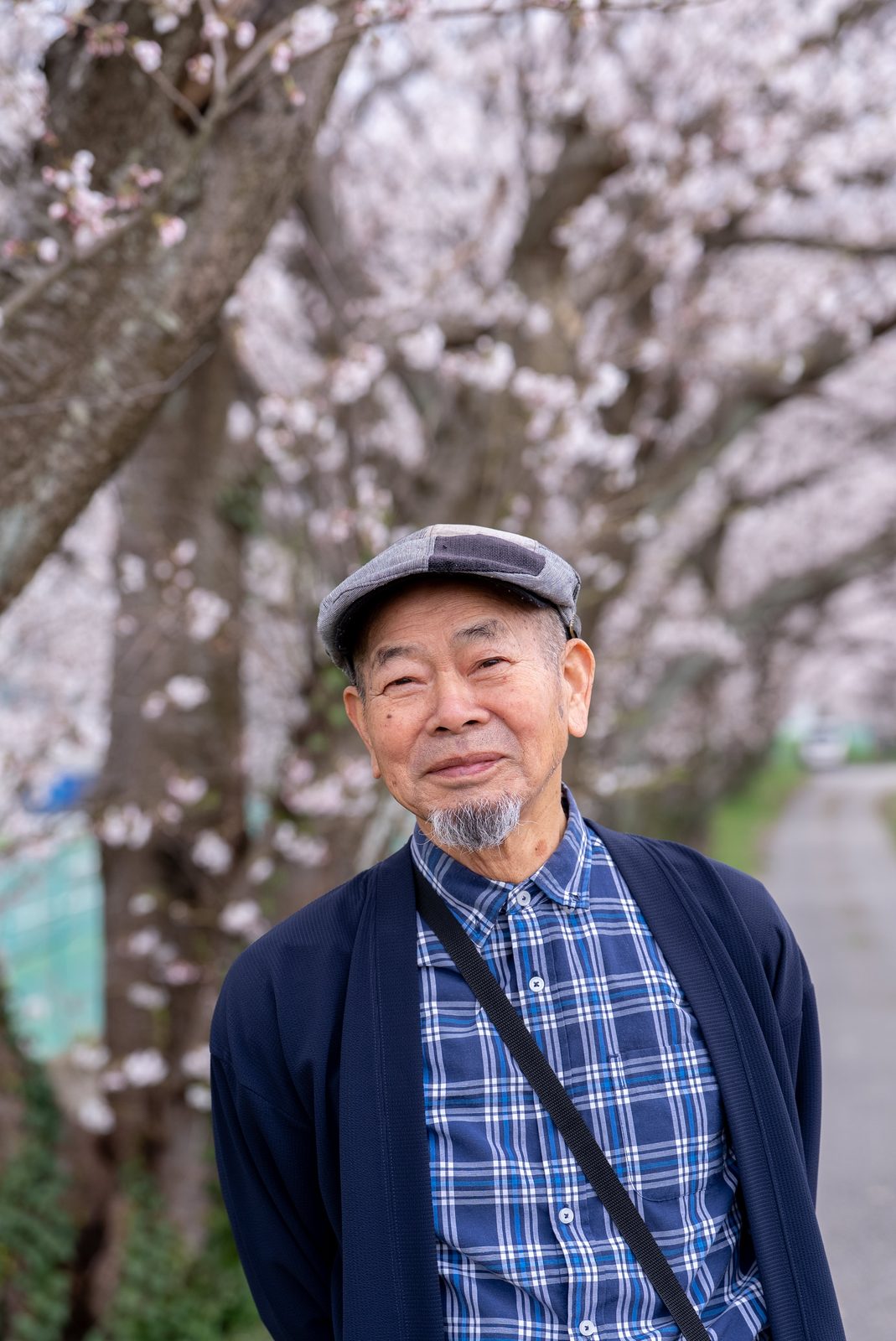 あらた坂の桜を背にした、帽子をかぶった祖父のポートレート