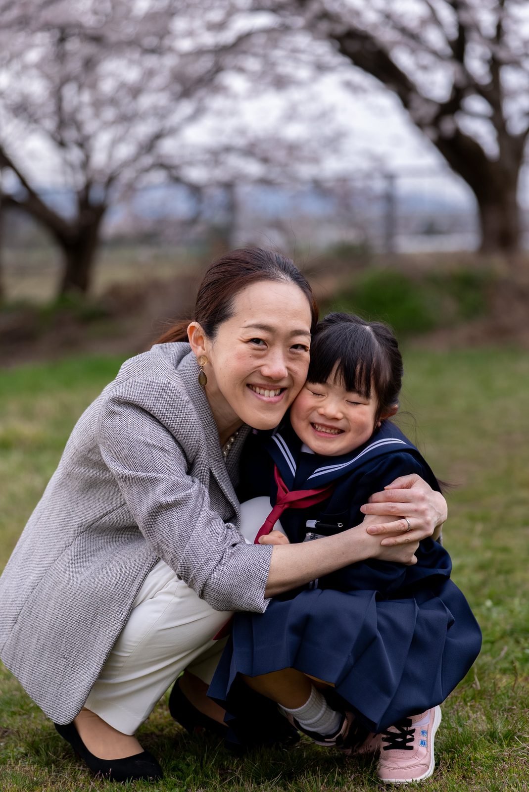 桜の下で母親と抱き合って笑う女の子