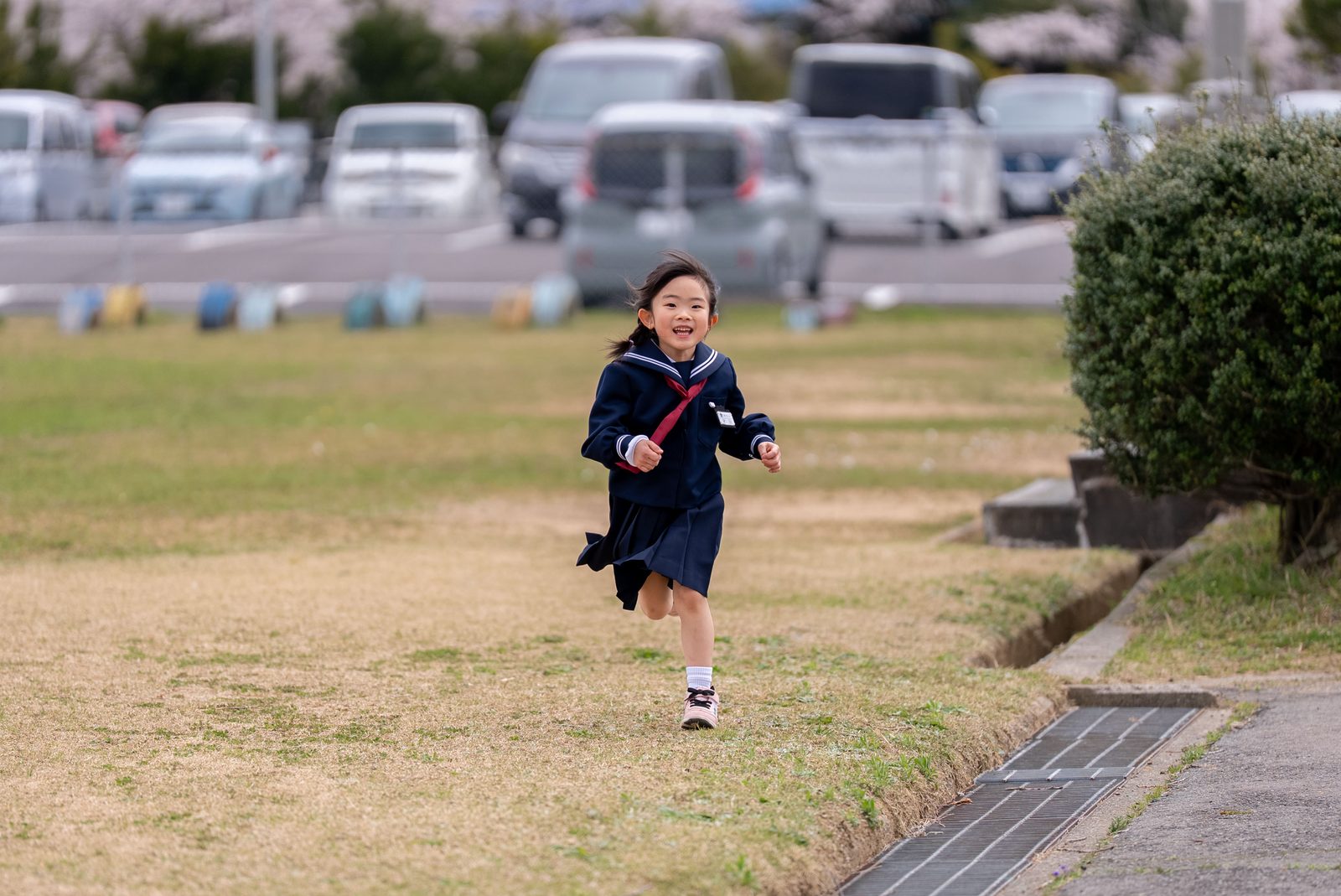 入学前の小学校の校庭を、制服姿で走る新一年生の女の子