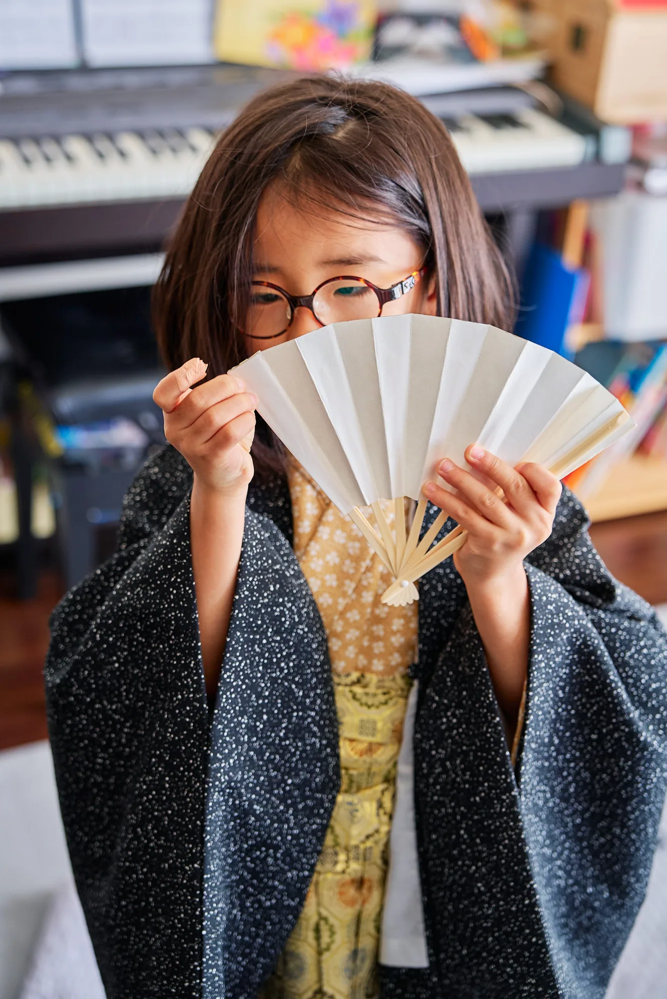 扇子で顔を隠しておどける七五三の男の子
