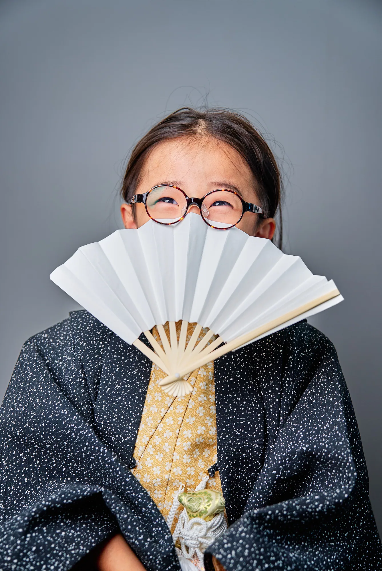 扇子で顔を隠す羽織姿の男の子のポートレート