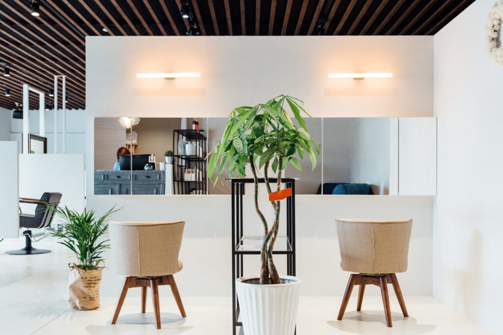 美容室の店内。鏡台と観葉植物のある明るい空間
