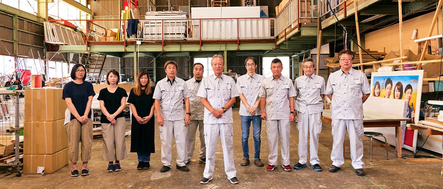 作業場に並んだ従業員10人の集合写真